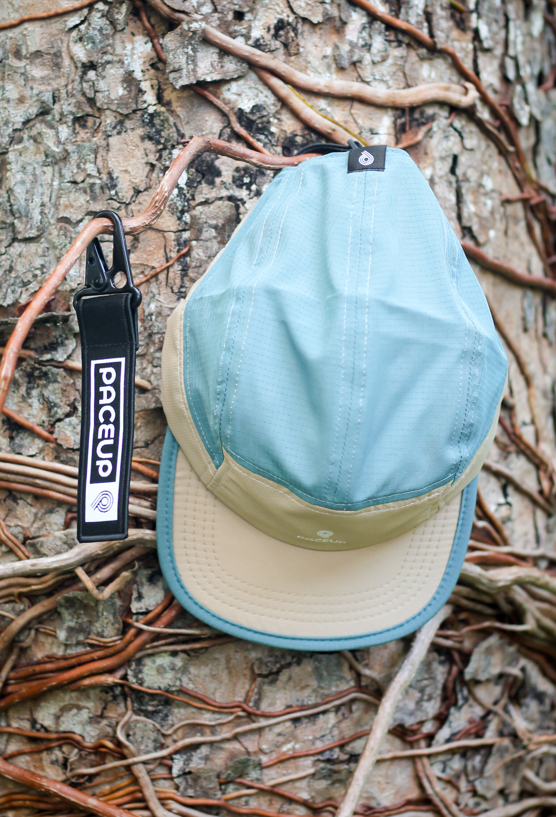 Gorra Paceup celeste sobre un tronco con llavero de la marca